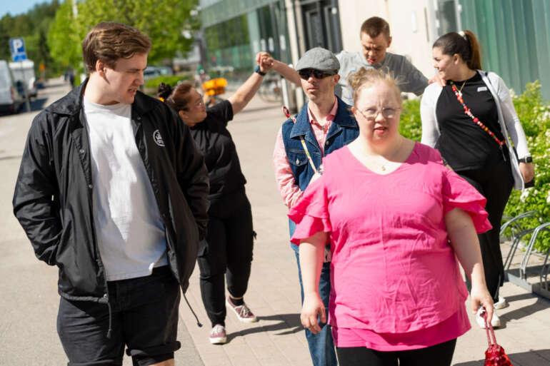 Joukko ihmisiä kävelelemässä jalkakäytävällä.